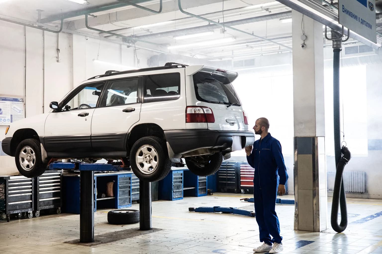 Mechanic inspecting a lifted SUV in a modern auto repair garage.