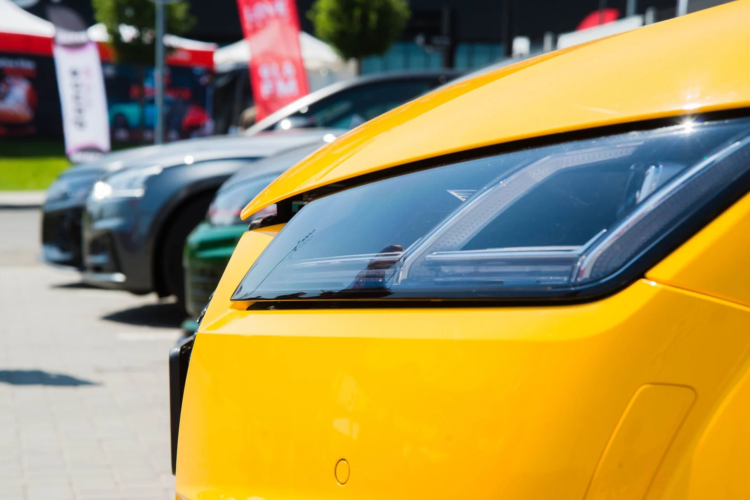 Vibrant yellow car headlight close-up in a sunny outdoor parking lot.